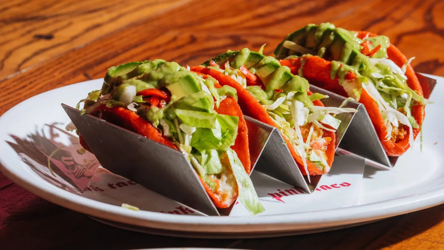 Three tacos on a white plate that says ' pinch ' on it